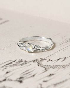 a silver ring sitting on top of a piece of paper with drawings in the background