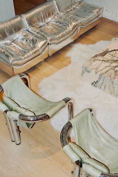 two silver chairs sitting on top of a hard wood floor next to a white rug