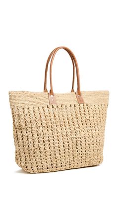 a straw bag with leather handles on the front and side, in natural color scheme