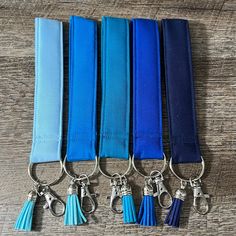 four keychains with blue tassels are lined up on a table