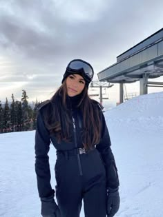 a woman standing on top of a snow covered slope wearing skis and goggles