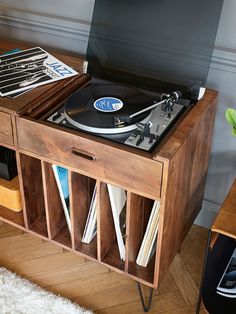 a record player sitting on top of a wooden cabinet next to a table with records