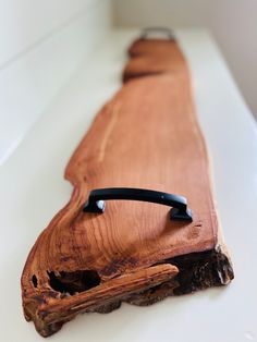 a piece of wood that is on top of a white counter with a black handle