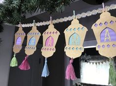 some paper hanging from a tree with tassels on it's ends and one has a castle in the middle