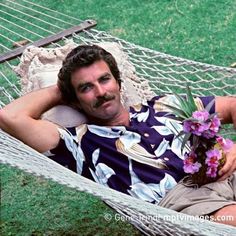 a man laying in a hammock with flowers on his chest and holding a flower