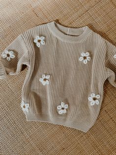 a sweater with white flowers on it sitting on a couch