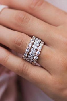 a woman's hand wearing a ring with three rows of diamonds on the band