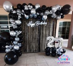 balloons and streamers decorate the entrance to a 21st birthday party in black and silver