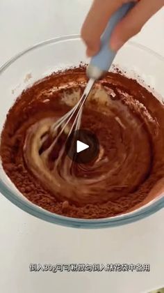 someone mixing chocolate in a glass bowl with a whisk on the side,