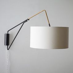 a white lamp hanging from the side of a wall next to a black light fixture