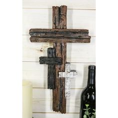 a wooden cross hanging on the wall next to a bottle of wine and a candle