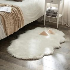 a white sheepskin rug is on the floor in front of a bed and nightstand