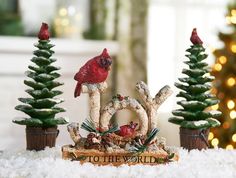 a christmas scene with red birds on top of the letters joy and two evergreen trees