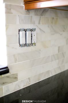 the light switch is mounted on the marble tile backsplash in this modern kitchen