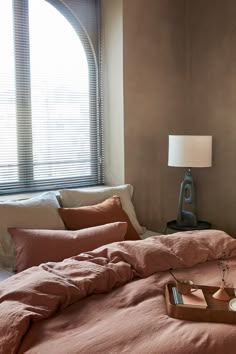 a bed with two trays on top of it in front of a large window