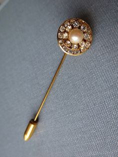 Round Rhinestone Pearl Stick Pin Double Ring of Clear Rhinestones Faux Pearl Bead Center Textured Gold Filigree Metal Base Gold Tone Body, End Cap Vintage from the 1970's Size: 5/8 x 2 1/2 inches Condition: Very good, pearl has no nacre loss, rhinestones are shiny, gold finish is good. More Stick Pins: http://etsy.me/2wQiXNb Gold Jeweled Brooches For Formal Occasions, Gold Costume Jewelry Pins For Wedding, Formal Gold Jeweled Brooches, Round Rhinestone Brooches For Formal Occasions, Gold Rhinestone Pins For Wedding, Elegant Brooch Pins For Vintage Events, Gold Rhinestone Wedding Pins, Round Formal Brooches With Rhinestones, Elegant Gold Pins With Rhinestones