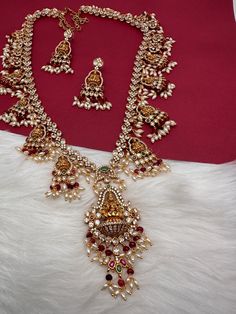 Goddess Lakshmi CZ Color Stone Rice Pearls Guttapusalu Necklace with matching earringsColor : GoldenSize : Necklace Length : 24 Inches; Earring Length : 2 Inches ApproxStones : CZ Red Green Stone Pearls Ruby Chandbali Temple Necklace For Festive Occasions, Festive Ruby Chandbali Temple Necklace, Diwali Temple Jewelry Sets With Latkans, Festive Ruby Bridal Necklace In Temple Jewelry Style, Temple Jewelry Sets With Chandbali Shape And Latkans, Temple Jewelry Sets With Chandbali Latkans, Red Kundan Temple Jewelry Set, Red Chandbali Temple Necklace With Stone Work, Temple Jewelry Sets Hand Set For Puja