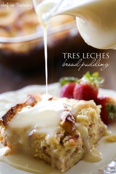 a piece of bread pudding on a white plate with strawberries and syrup being drizzled over it