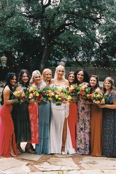 a group of women standing next to each other holding bouquets in their hands and smiling at the camera