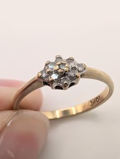 a close up of a person's hand holding a gold ring with three diamonds