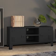 a black cabinet with two drawers and a plant on top in front of a gray wall