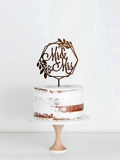 a wedding cake with the word mr and mrs on top, sitting on a pedestal