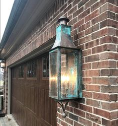 an old fashioned light hanging on the side of a brick building next to a garage