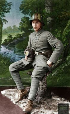 an old black and white photo of a boy in uniform sitting on a tree stump