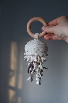 a hand holding a wooden ring with a crocheted decoration hanging from it