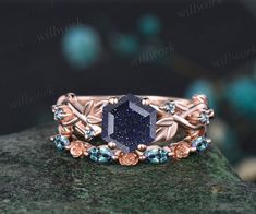 a ring with a blue stone surrounded by flowers and leaves on top of a rock