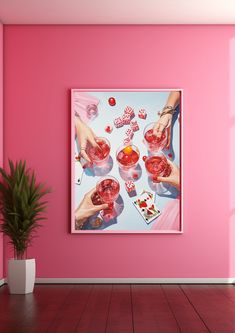 a pink room with two hands holding drinks and playing cards on the table next to a potted plant