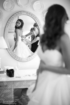 the bride is looking at her reflection in the mirror