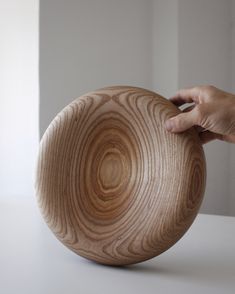 a person holding a wooden bowl on top of a table