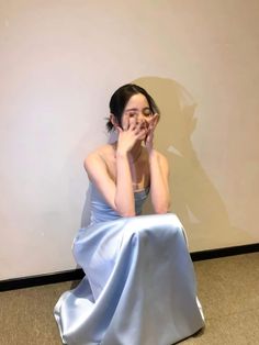 a woman sitting on the floor in a blue dress