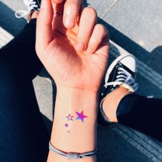 a woman's wrist tattoo with stars on it