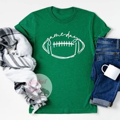 We know that the spirit of gameday begins with your outfit! Make sure you're ready for the season with our trendy gameday shirts. The perfect shirts for Football season or any gameday! These shirts are soft and lightweight - great to wear every day. Stylish enough to dress up or down! Sporty T-shirt For Game Day During Football Season, Game Day T-shirt With Screen Print For Sports Season, Team Colors Tops For Game Day, Pre-shrunk Sports Fan T-shirt For Game Day, Team Spirit Tops For Game Day Sports Season, White Casual Top For Tailgating, Casual White Top For Tailgating, Football Season Fan Apparel Tops, Varsity Team-colored Tops For Game Day