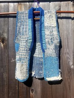 an old piece of cloth hanging from a clothes line on a wooden fence with some wood pegs in the background