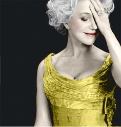 a black and white photo of a woman holding her hand up to her face while wearing a dress