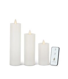 three white candles sitting next to each other with a remote control in front of them