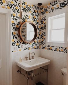 a white sink sitting under a bathroom mirror next to a wall mounted faucet