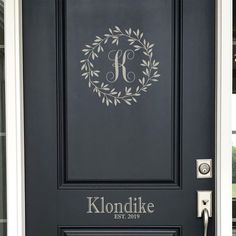 the front door is painted black and has a monogrammed wreath on it