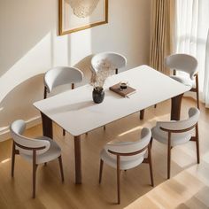 a dining room table with four chairs and a vase on the top, in front of a window