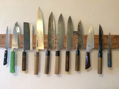 knives are lined up on a wall with wooden handles and green blades attached to them