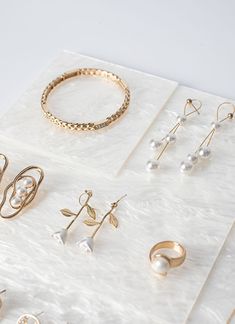 several pairs of earrings and rings on a white surface