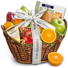 a basket filled with fruit and cheese next to sliced oranges, apples, and crackers