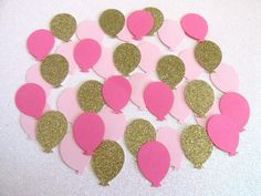 pink and gold heart shaped confetti cut out from paper on a white surface