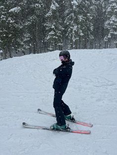 a person riding skis down a snow covered slope with trees in the back ground