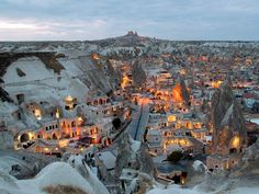 an aerial view of a town in the middle of mountains and rocks with lights on them