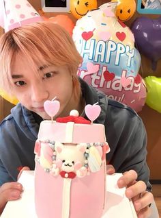 a person holding up a cake in front of their face with hearts on it and balloons behind them