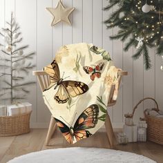 a chair covered in a blanket with butterflies on it next to a christmas tree and presents